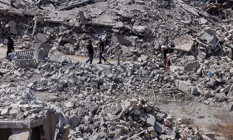 People walk past buildings destroyed by an Israeli airstrike during the interim period following the US-Iran deal, in Nabatieh, southern Lebanon on June 26, 2026. &mdash; Reuters