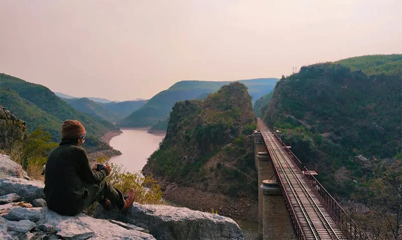 A visitor sits on a rock beside the railway bridge over the Soan River, a masterpiece of colonial-era engineering.