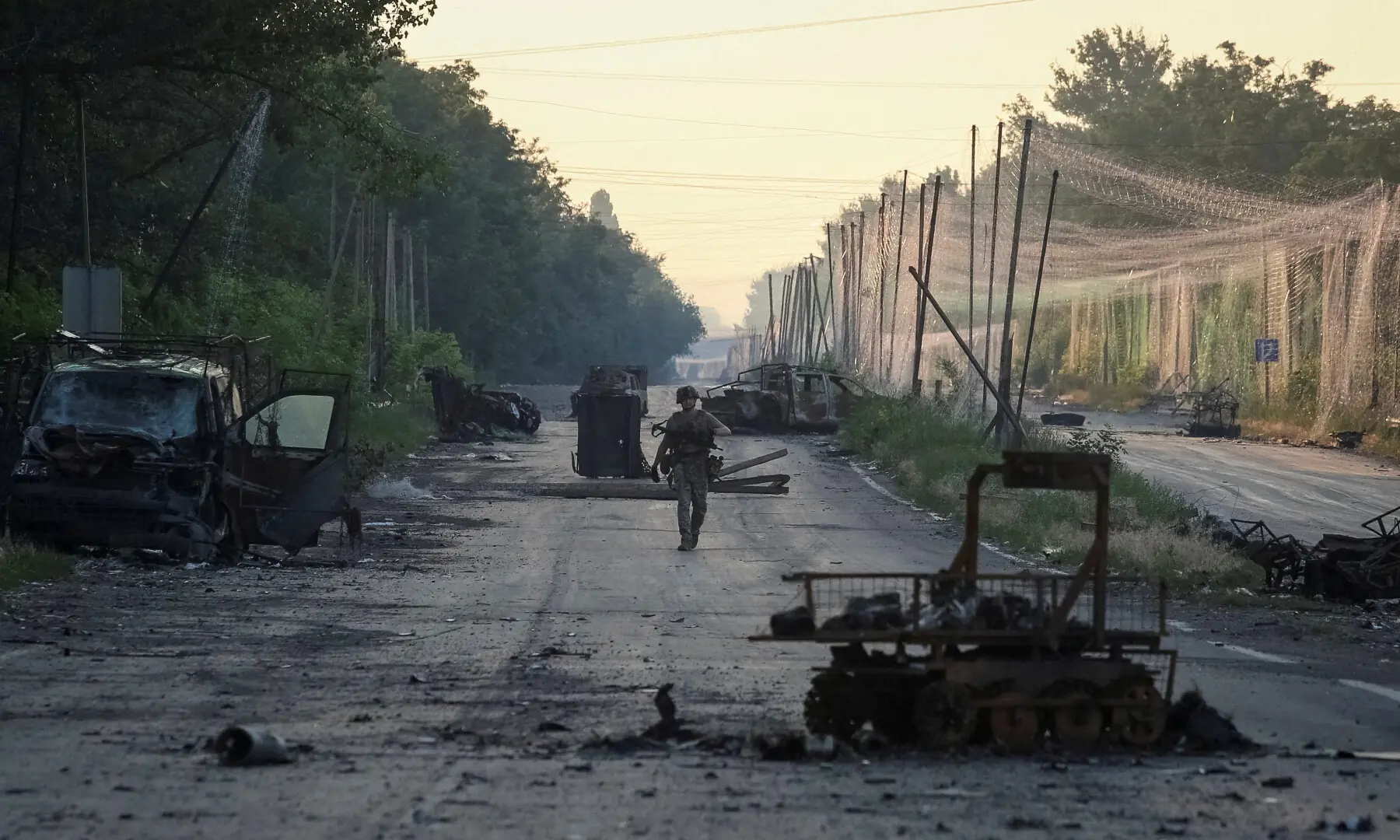 A serviceman of the consolidated Brigade &lsquo;Khyzhak&rsquo; of the Ukrainian Patrol Police Department walks along a road near anti-drone nets and destroyed military vehicles as he takes part in a mission to protect a road from Russian drones between frontline towns of Druzhkivka and Kostiantynivka, in the Donetsk region, Ukraine on June 24, 2026. &mdash; Reuters