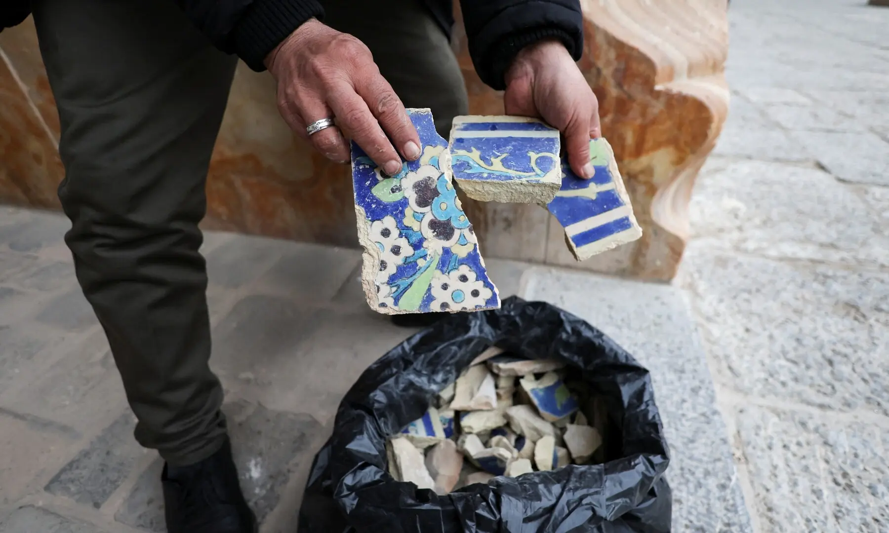 A person holds broken decorative tile fragments at the Shah Mosque located at the southern edge of Naqsh-e Jahan Square, a Unesco World Heritage site, amid the US-Israeli conflict with Iran, in Isfahan, Iran, on March 23, 2026. &mdash; Reuters
