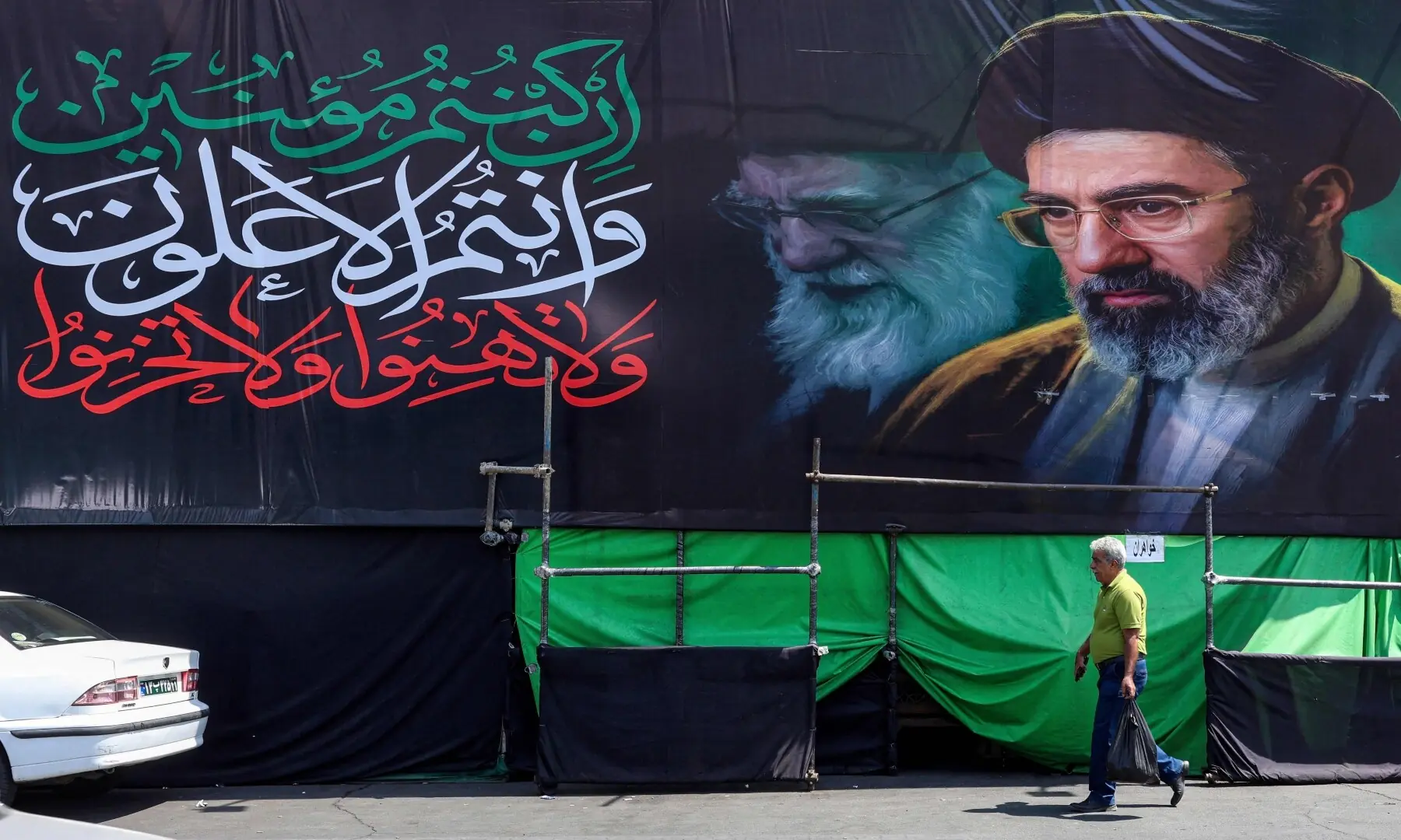A man walks past a huge mourning banner depicting Iran&rsquo;s current supreme leader Ayatollah Mojtaba Khamenei and his late father Ayatollah Ali Khamenei, who was killed in a strike on the first day of the US-Israeli war against the Iran on February 28, set up along a road in Tehran on June 30, 2026 ahead of Ali Khamenei&rsquo;s funeral. &mdash; AFP