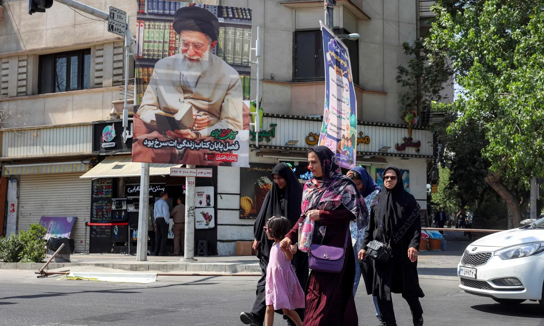 People cross a road past a mourning billboard depicting Iran&rsquo;s slain supreme leader Ali Khamenei, who was killed in a strike on the first day of the US-Israeli war against the Iran on February 28, in Tehran, Iran on June 30, 2026 ahead of his public funeral. &mdash; AFP