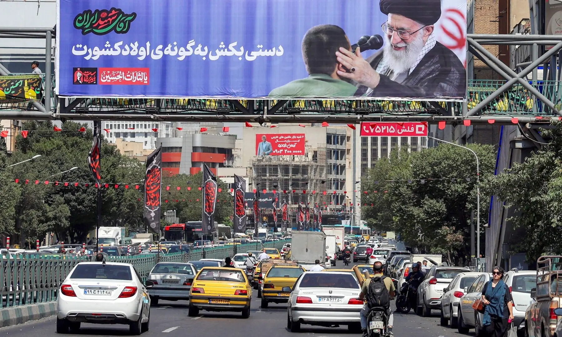 People drive under a bridge adorned with a mourning billboard depicting Iran&rsquo;s slain supreme leader Ali Khamenei, who was killed in a strike on the first day of the US-Israeli war against the Iran on February 28, in Tehran, Iran on June 30, 2026 ahead of his public funeral. &mdash; AFP