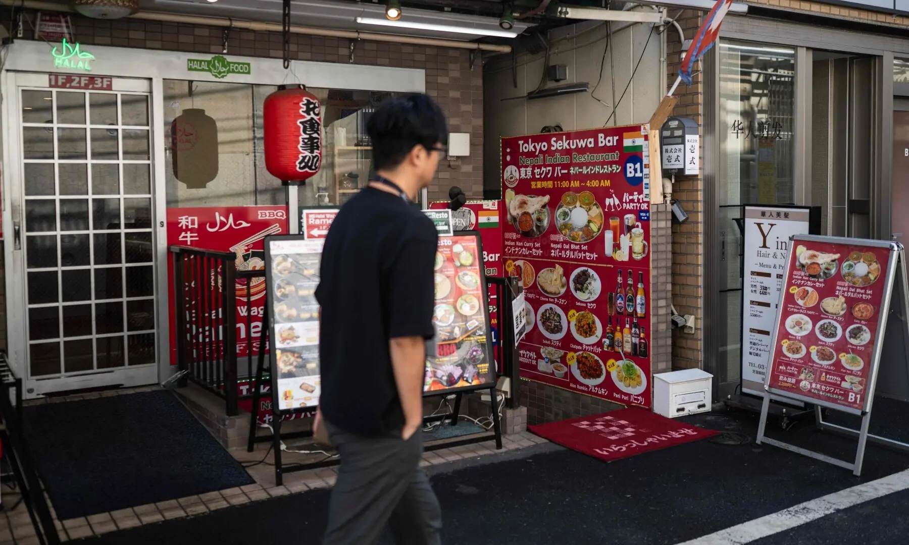 A man walks past a South Asian restaurant in the Okubo–Shin area, one stop north of Shinjuku metro, in Tokyo on June 12, 2026, a neighbourhood known for its large immigrant communities, including Korean, Southeast Asian and South Asian residents. — AFP