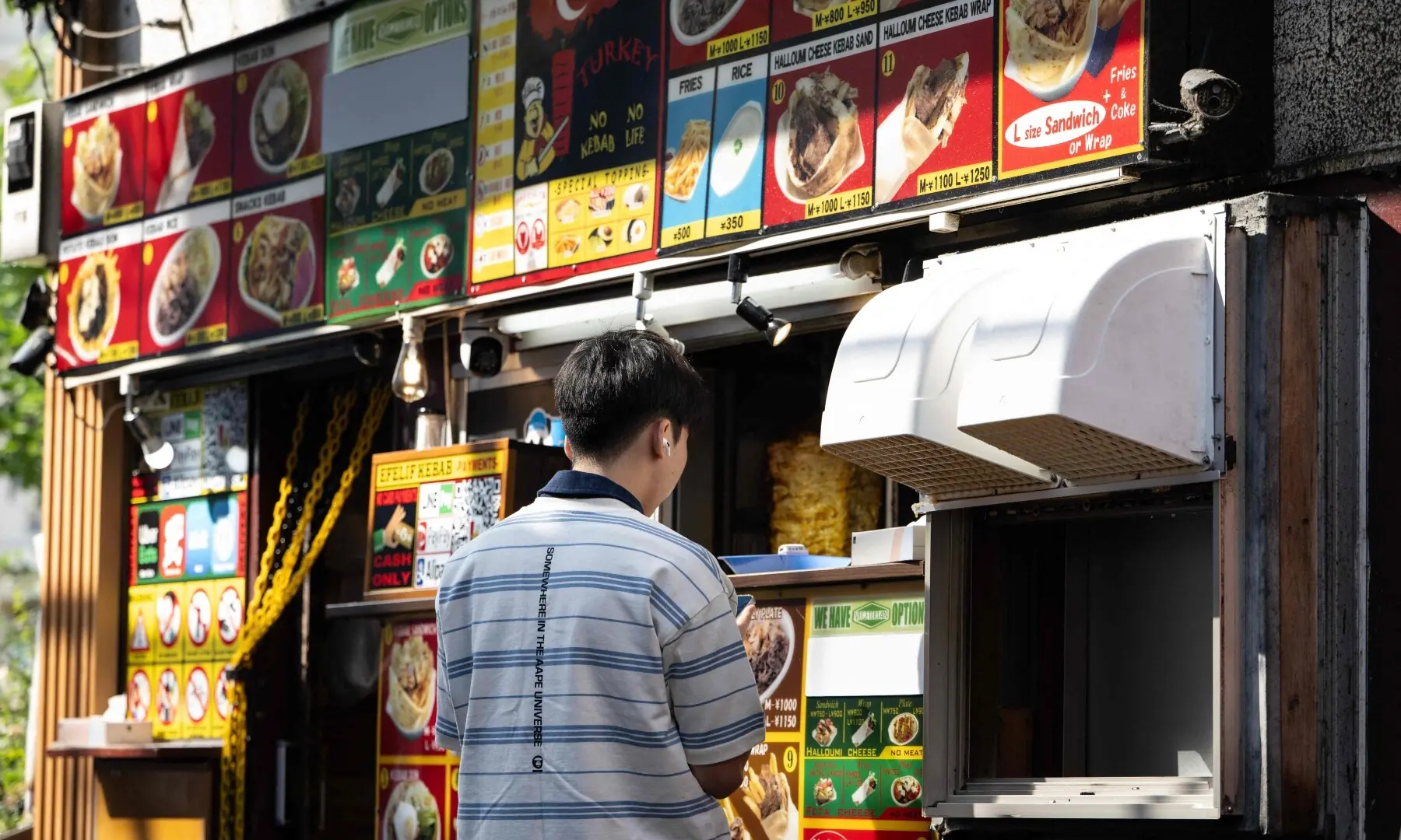 A man orders from a kebab shop in the Okubo–Shin area, in Tokyo on June 12, 2026, a neighbourhood known for its large immigrant communities, including Korean, Southeast Asian and South Asian residents. — AFP