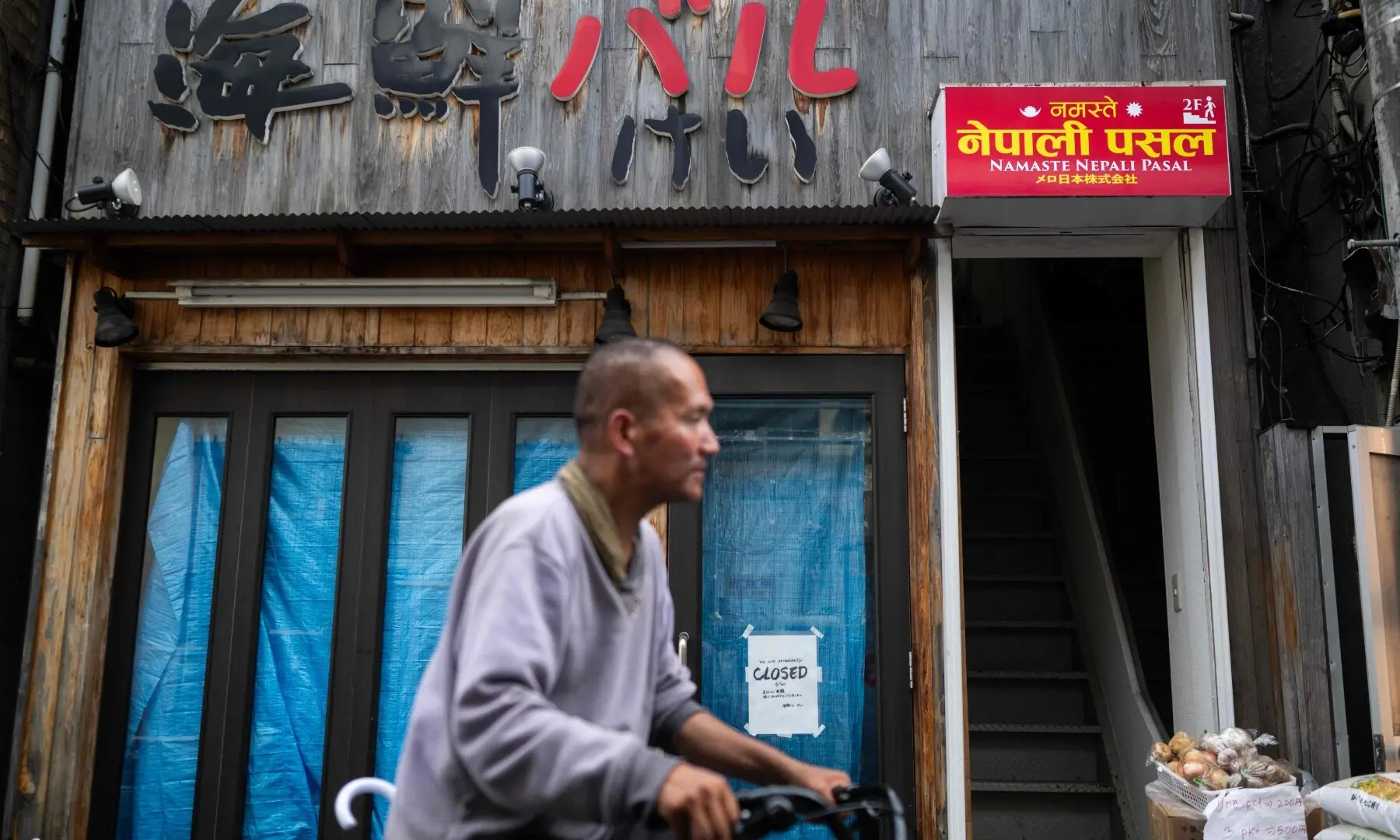 A man cycles past a Nepali restaurant in the Okubo–Shin area, one stop north of Shinjuku metro, in Tokyo on June 12, 2026, a neighbourhood known for its large immigrant communities, including Korean, Southeast Asian and South Asian residents. — AFP
