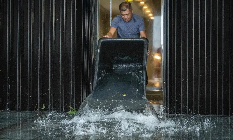 A hotel staff member removes water that leaked into a building during heavy rain brought by Super Typhoon Bavi in Guam on July 6, 2026. —AFP