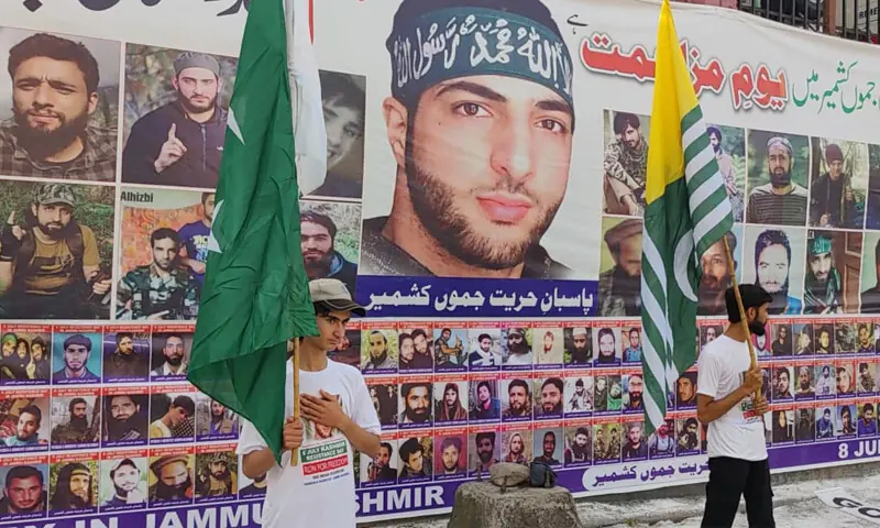 Two young boys holding flags of Pakistan and Azad Kashmir stand against a giant backdrop featuring portrait of Burhan Wani and other Kashmiri martyrs in Muzaffarabad on Wednesday. — Photo by the writer Two young boys holding flags of Pakistan and Azad Kashmir stand against a giant backdrop featuring portrait of Burhan Wani and other Kashmiri martyrs in Muzaffarabad on Wednesday. — Photo by the writer