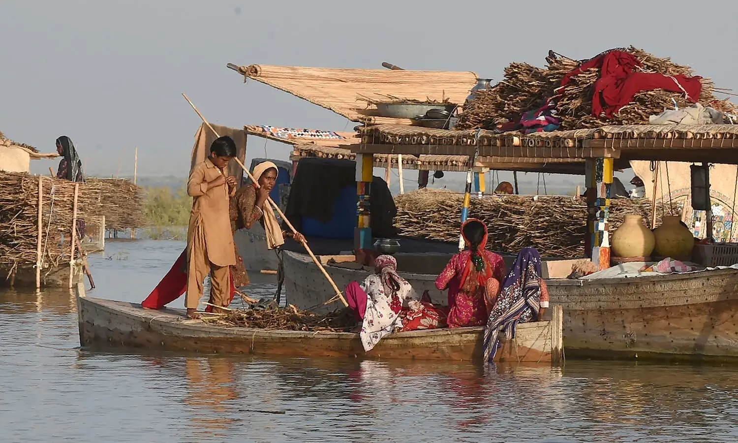 In this photograph taken on September 9, 2016, Mohanna women shuttle on a satellite boat to their floating boathouse on Manchar lake, a 223 square kilometre natural water reservior in southern Pakistan. Mohammed Yusuf is a fatalist: years from now his rare floating village may disappear from Pakistan's Manchar Lake because wastewater poured into it for three decades has made it inhospitable, for the fish as well as for the fishermen. / AFP PHOTO In this photograph taken on September 9, 2016, Mohanna women shuttle on a satellite boat to their floating boathouse on Manchar lake, a 223 square kilometre natural water reservior in southern Pakistan. Mohammed Yusuf is a fatalist: years from now his rare floating village may disappear from Pakistan's Manchar Lake because wastewater poured into it for three decades has made it inhospitable, for the fish as well as for the fishermen. / AFP PHOTO