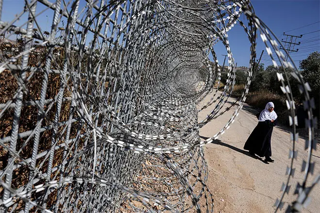 A woman walks past a fencing installed by the Israeli army in Sinjil. The fencing closed off four of the five entrances to the town in occupied West Bank.—Reuters A woman walks past a fencing installed by the Israeli army in Sinjil. The fencing closed off four of the five entrances to the town in occupied West Bank.—Reuters