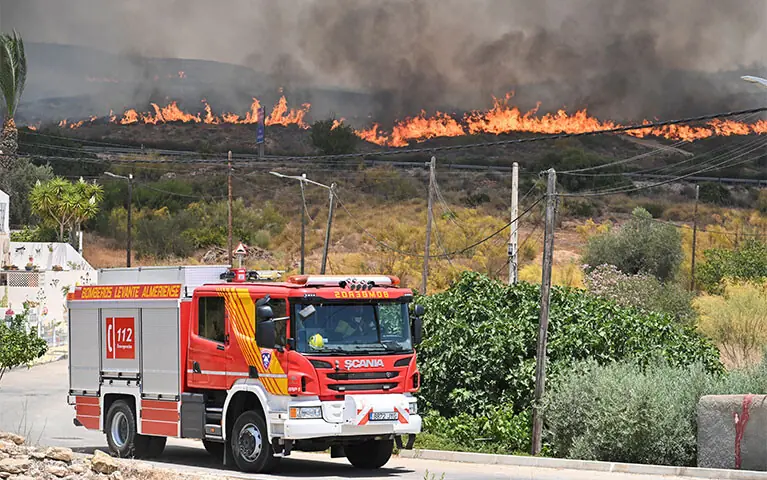 A firefighting vehicle drives by as smoke and flames rise during deadly wildfires affecting Spain’s Almeria province.—Reuters A firefighting vehicle drives by as smoke and flames rise during deadly wildfires affecting Spain’s Almeria province.—Reuters
