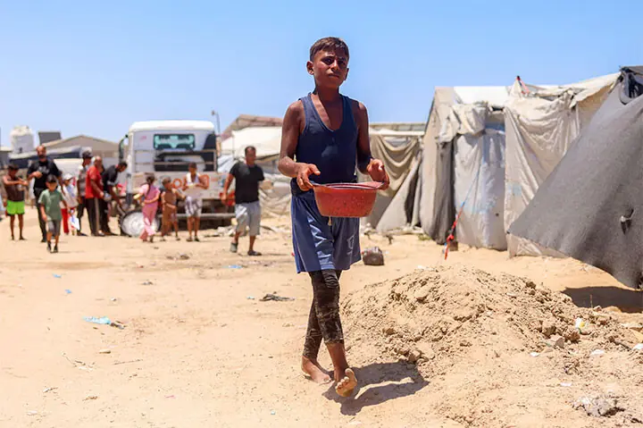 A BOY with a pot walks past tents for displaced people in Khan Yunis, southern Gaza Strip.—AFP A BOY with a pot walks past tents for displaced people in Khan Yunis, southern Gaza Strip.—AFP