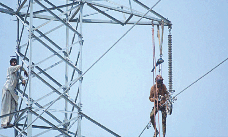 Image shows workers working on an electricity pole. &mdash; AFP/File