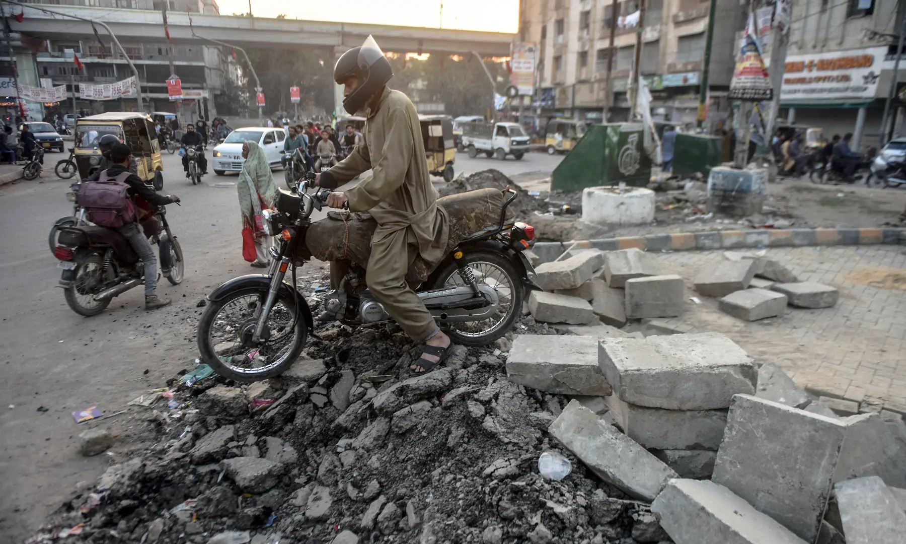 A motorcyclist navigates over a broken road in Karachi. &mdash; White Star