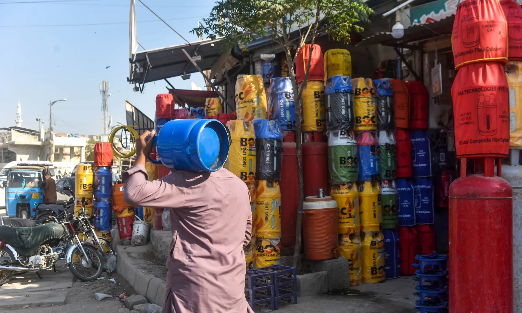 A man carries a gas cylinder over his shoulder in Karachi. &mdash; White Star