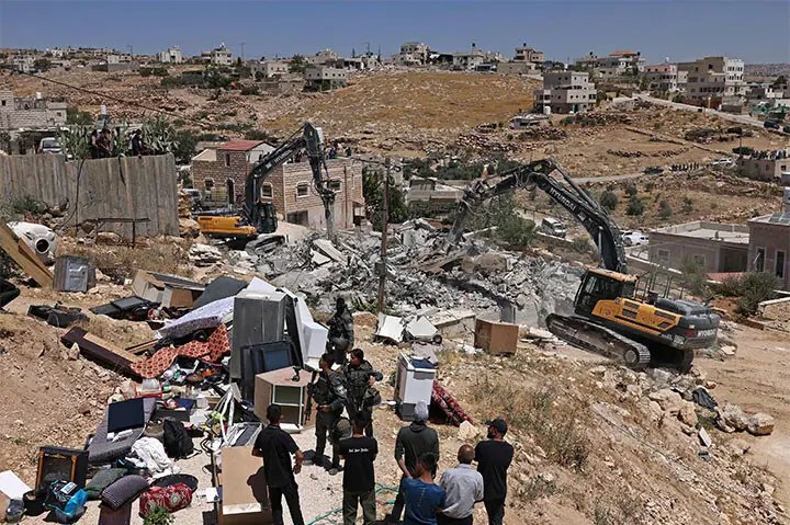 Palestinians watch Israeli excavators demolishing a house in the village of Al Dirat, south of Hebron in the occupied West Bank.—AFP Palestinians watch Israeli excavators demolishing a house in the village of Al Dirat, south of Hebron in the occupied West Bank.—AFP
