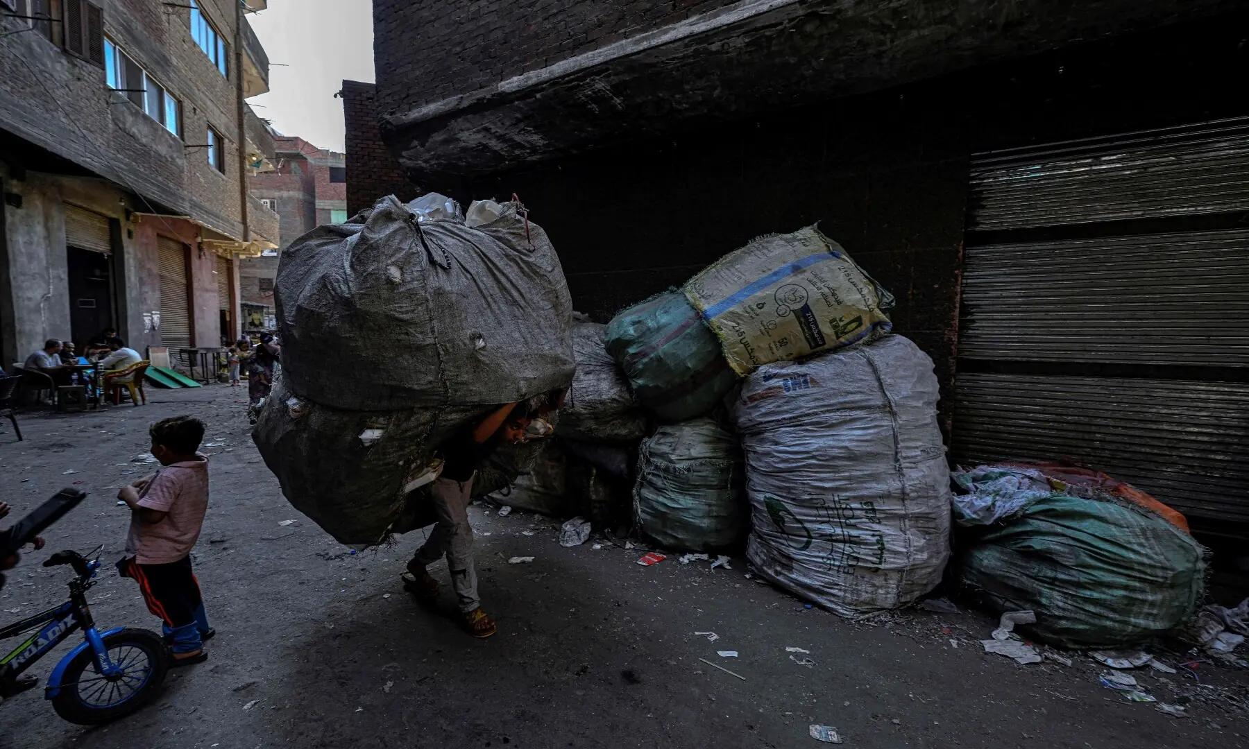 An Egyptian man carries a large bag filled with rubbish at the garbage city in the Manshiyet Nasser neighbourhood in Cairo on July 6, 2026. — AFP