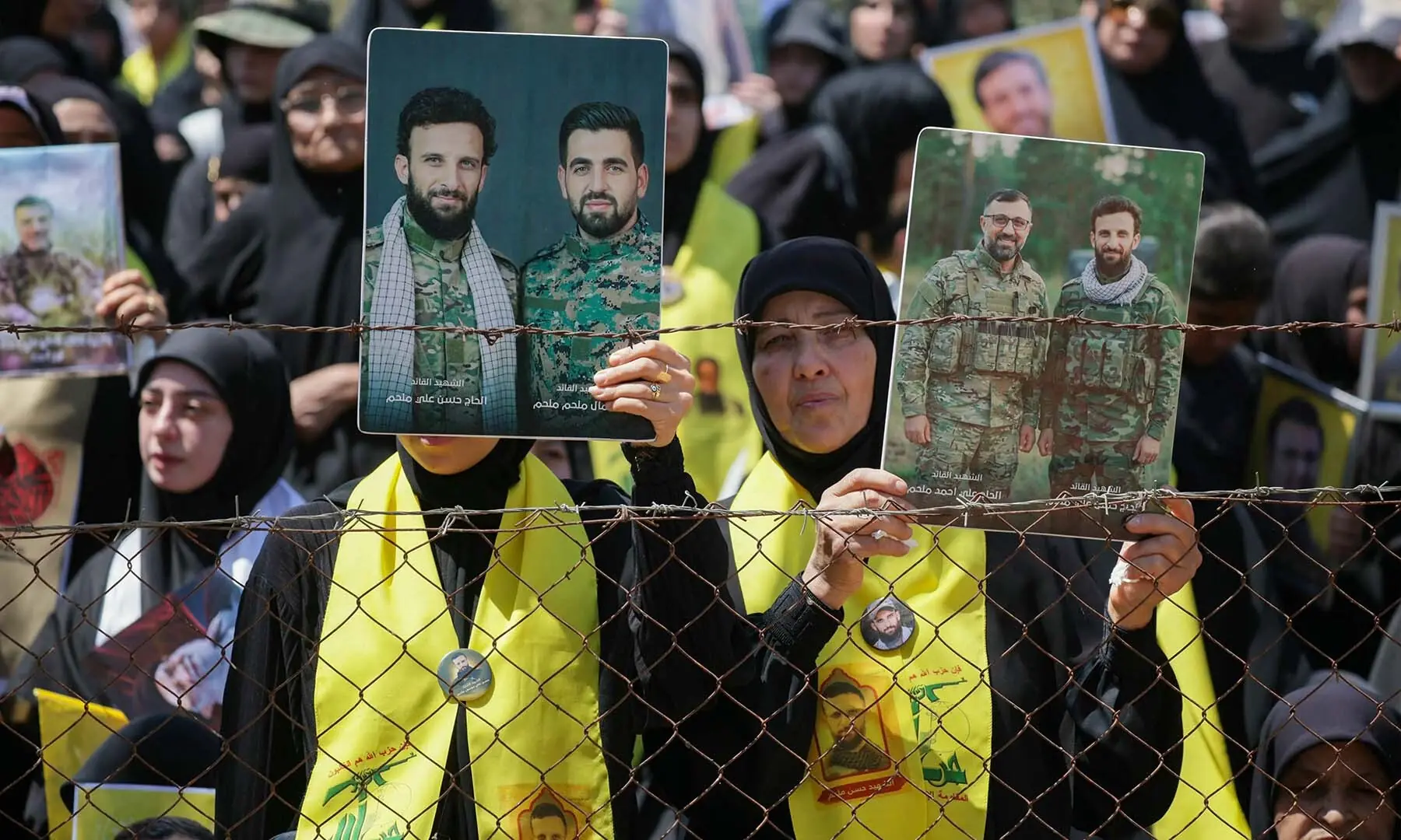 Women hold portraits of Hezbollah fighters who were killed in clashes with the Israeli army during a mass funeral in the southern Lebanese village of Majdel Selm on July 18, 2026. &mdash; AFP