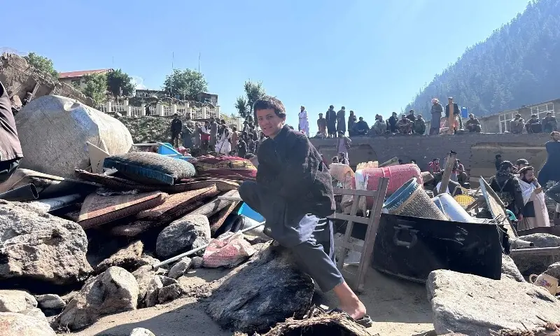 An Afghan boy sits with his belongings amidst the rubble following flash floods in Parun town in Afghanistan’s Nuristan province, on July 21, 2026. — AFP