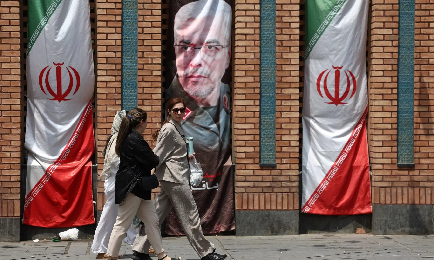 Iranian women walk past a banner with a picture of the former Chief of Staff of the Iranian Armed Forces, Mohammad Bagheri, in Tehran, Iran, July 20, 2026. — Reuters