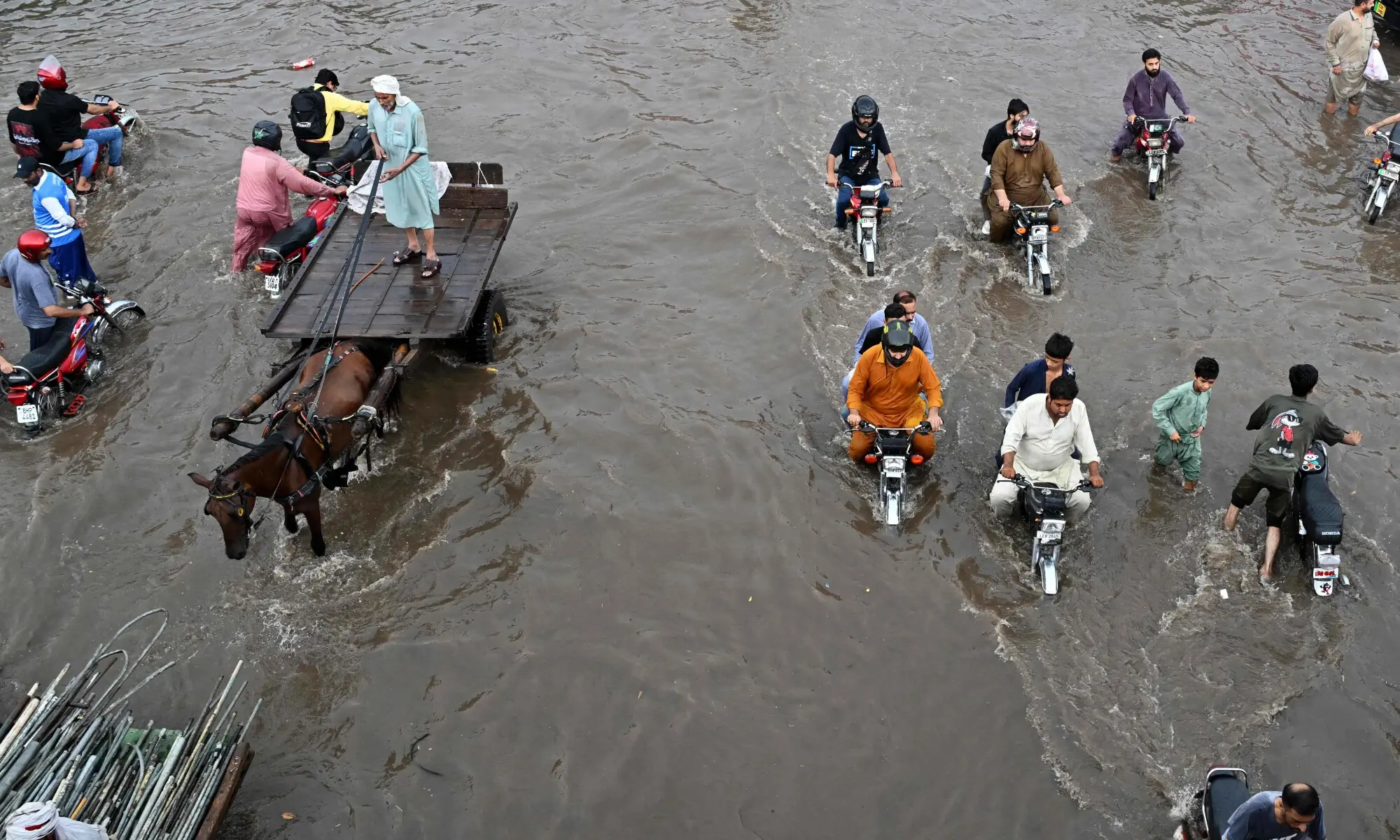 Commuters wade through a flooded street after heavy rainfall in Lahore on July 22, 2026. &mdash; AFP