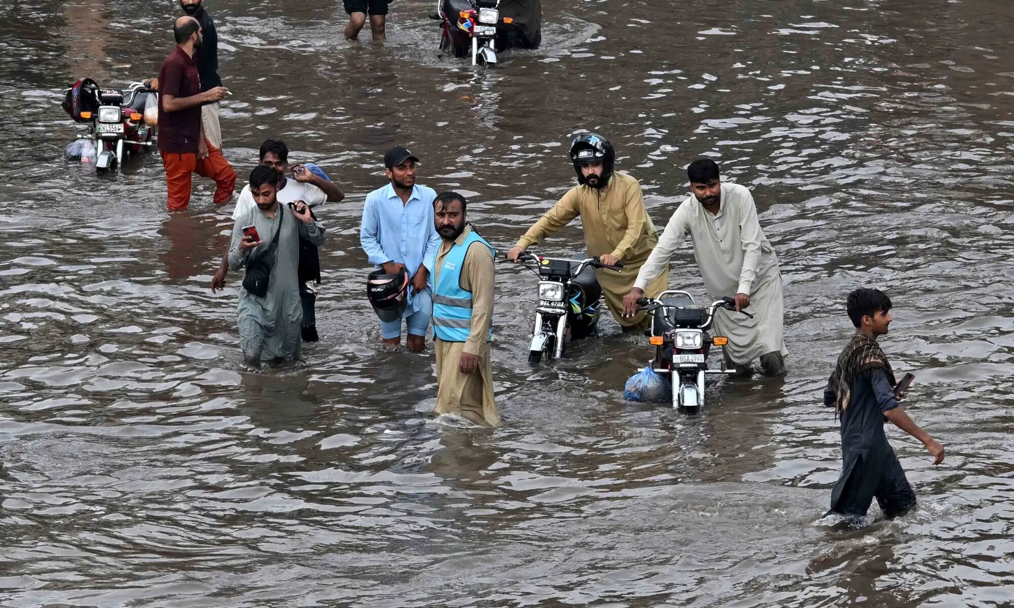 People wade through a flooded street after heavy rainfall in Lahore on July 22, 2026. — AFP People wade through a flooded street after heavy rainfall in Lahore on July 22, 2026. — AFP