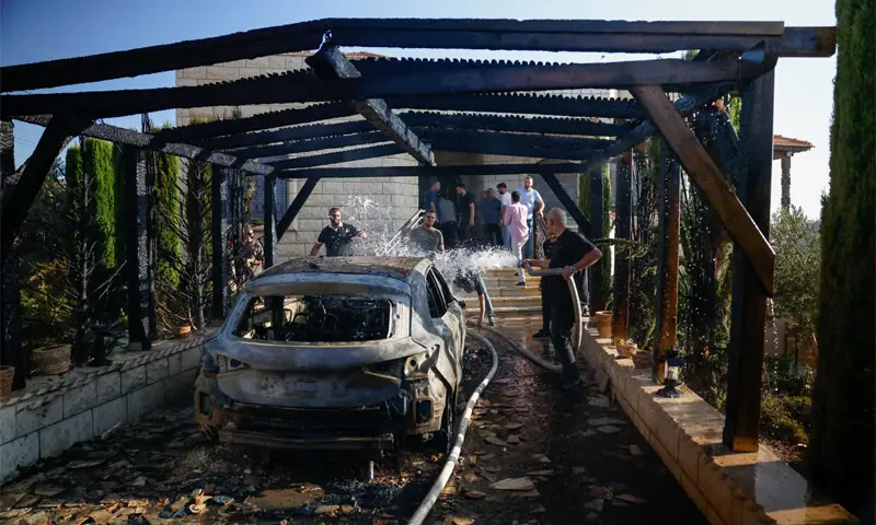 A PALESTINIAN man pours water on a burnt-out car, which was set on fire by Israeli settlers, in Sarra near Nablus.—Reuters A PALESTINIAN man pours water on a burnt-out car, which was set on fire by Israeli settlers, in Sarra near Nablus.—Reuters