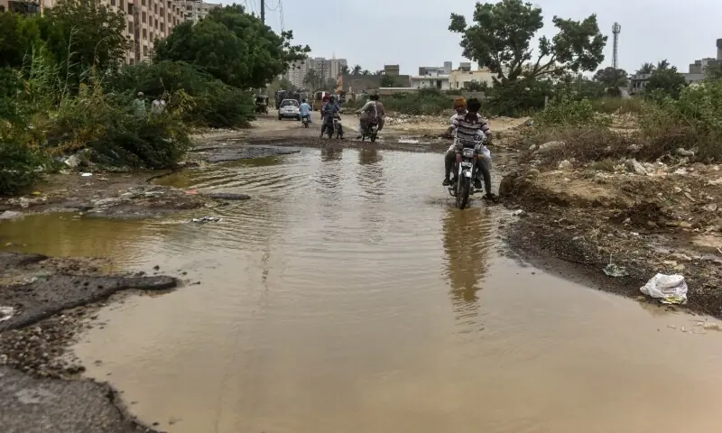 Motorcyclists cross water accumulated on a road in Karachi's Gulistan-i-Jauhar.—Fahim Siddiqi / White Star Motorcyclists cross water accumulated on a road in Karachi's Gulistan-i-Jauhar.—Fahim Siddiqi / White Star