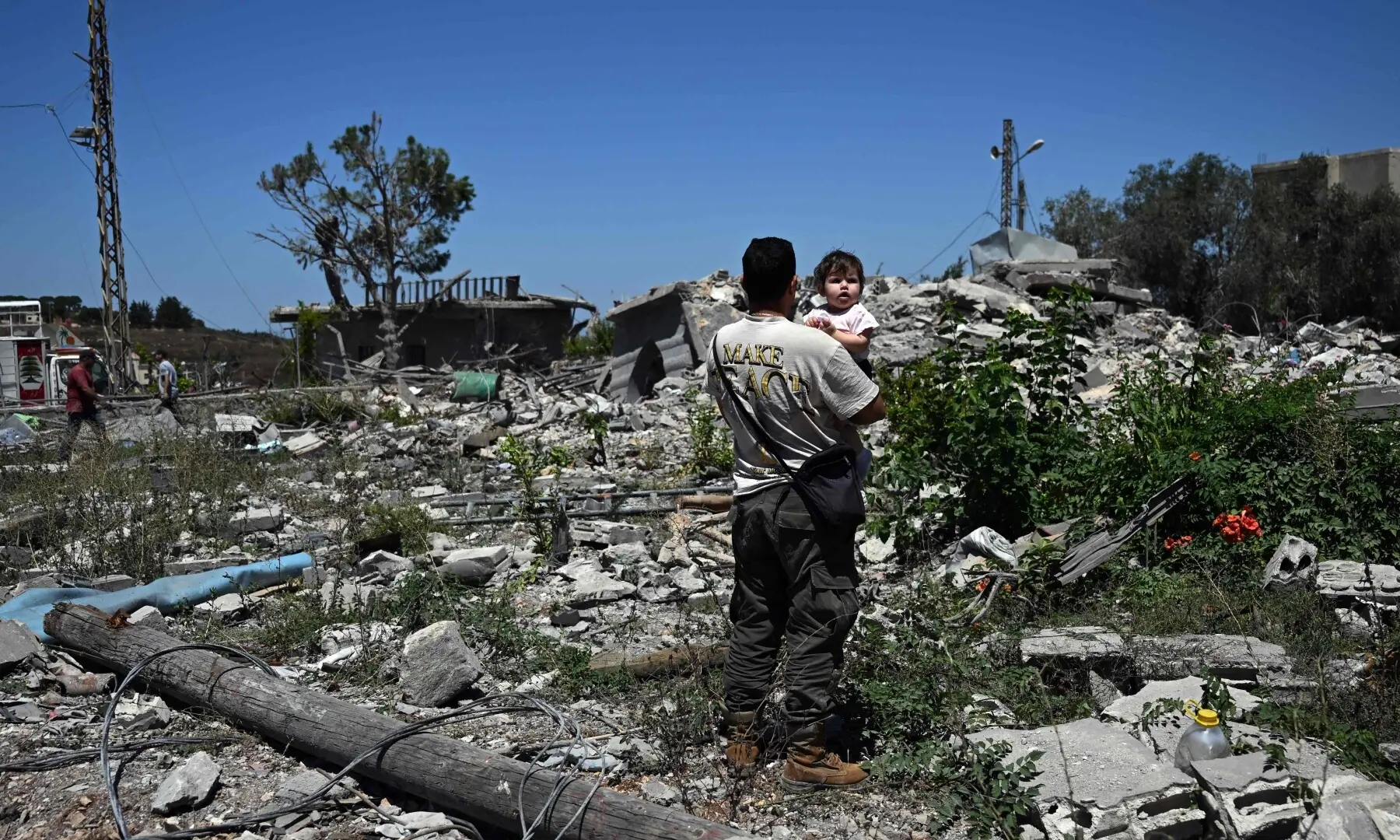 A man carries his niece on the rubble of his house in Zawtar al-Gharbiya on July 28, 2026, as residents return to inspect their homes after the Lebanese army deployed to the southern village last week as part of a framework deal reached with Israel. &mdash; AFP