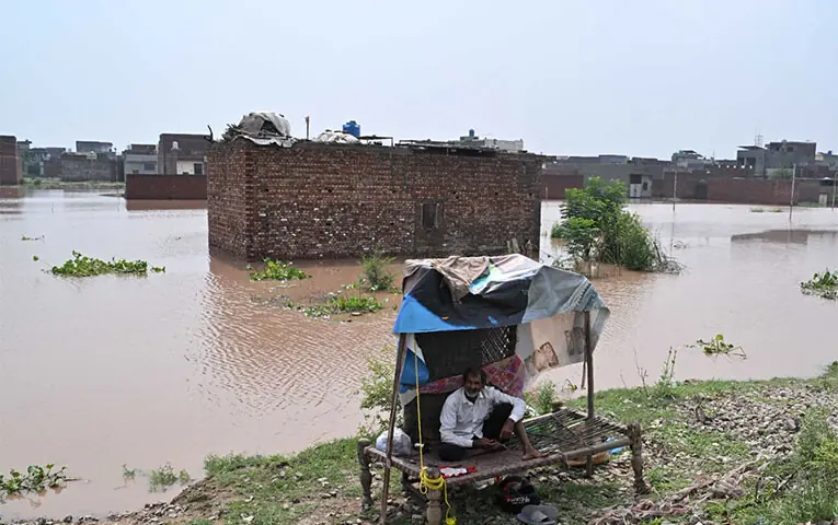 A DISPLACED man sits in an improvised shelter outside the submerged Pathan Colony neighbourhood, on the outskirts of Lahore.—M. Arif / White Star A DISPLACED man sits in an improvised shelter outside the submerged Pathan Colony neighbourhood, on the outskirts of Lahore.—M. Arif / White Star