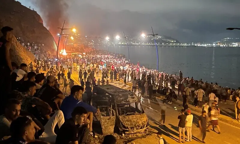 Migrants gather around a torched vehicle while waiting for a chance to cross to the Spanish enclave of Ceuta, on the Moroccan side of the border in Fnideq, Morocco, July 31, 2026. — Reuters