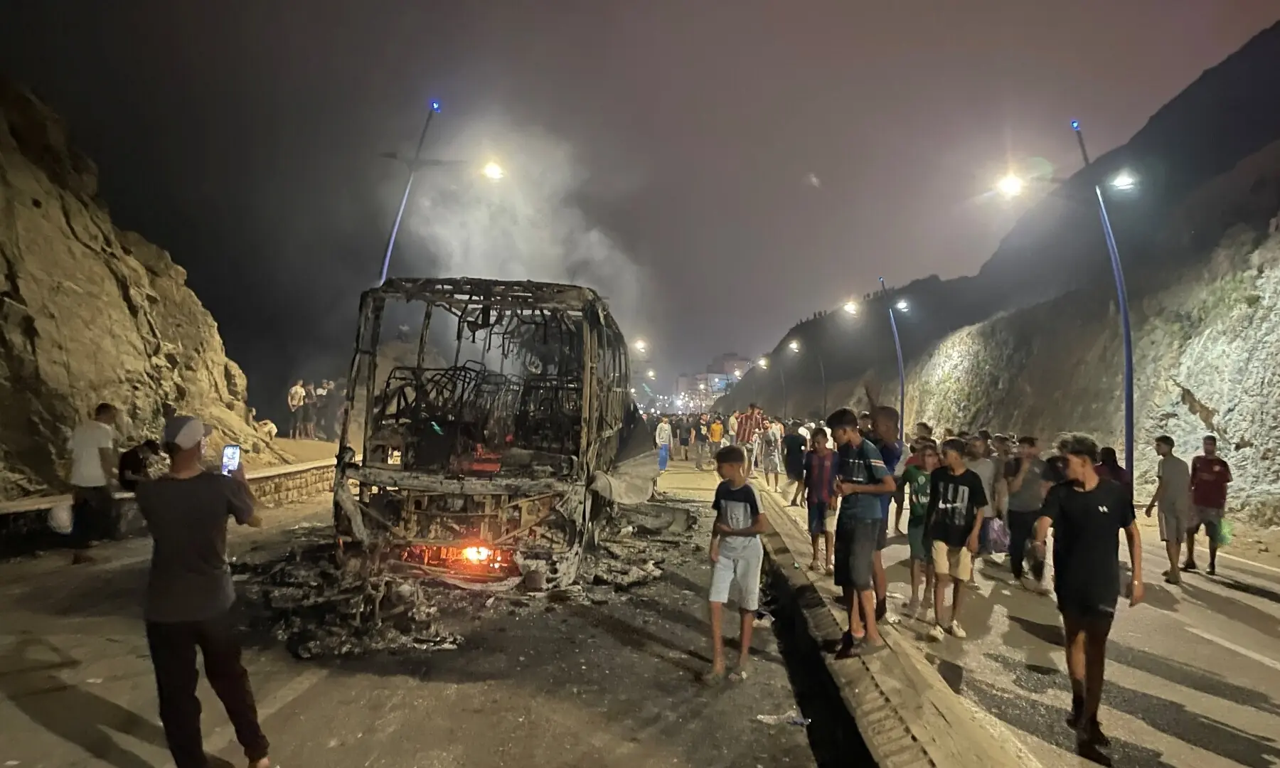 Migrants gather around a torched vehicle while waiting for a chance to cross to the Spanish enclave of Ceuta, on the Moroccan side of the border in Fnideq, Morocco, July 31, 2026. — Reuters