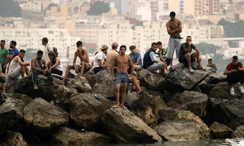 Migrants sit on rocks after swimming through the waters close to the border with Morocco to enter Spain's Ceuta enclave on July 31, 2026. — AFP Migrants sit on rocks after swimming through the waters close to the border with Morocco to enter Spain's Ceuta enclave on July 31, 2026. — AFP