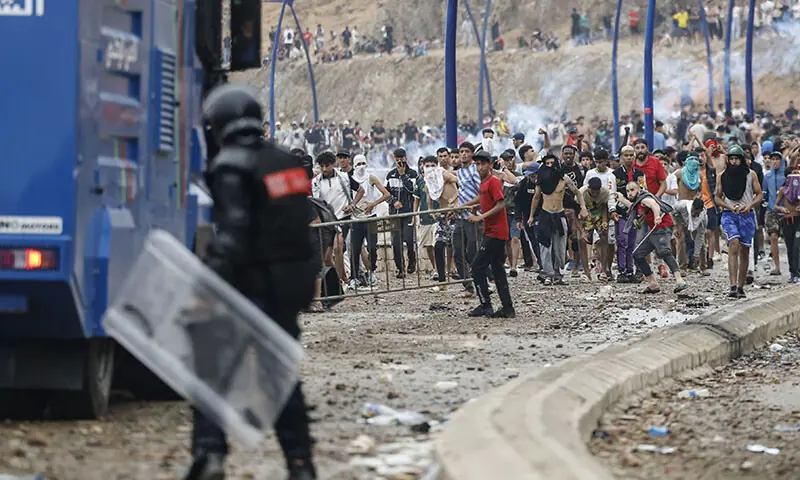 Moroccan security forces clash with migrants attempting to cross into Spain's North African enclave of Ceuta near the town of Fnideq, on the Morocco-Spain border, on July 31, 2026. The European Union on July 31 scrambled to contain one of the largest migrant crises faced by the block in recent years, after tens of thousands of people poured into into Spain's North African Ceuta enclave in just days. (Photo by Abdel Majid BZIOUAT / AFP)