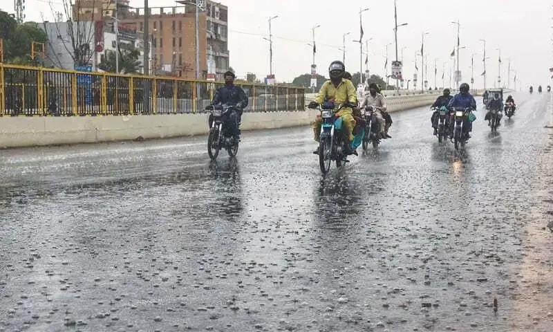 In this file photo, motorcyclists drive through North Nazimabad in Karachi during rainfall.&mdash;Fahim Siddiqi/White Star/File