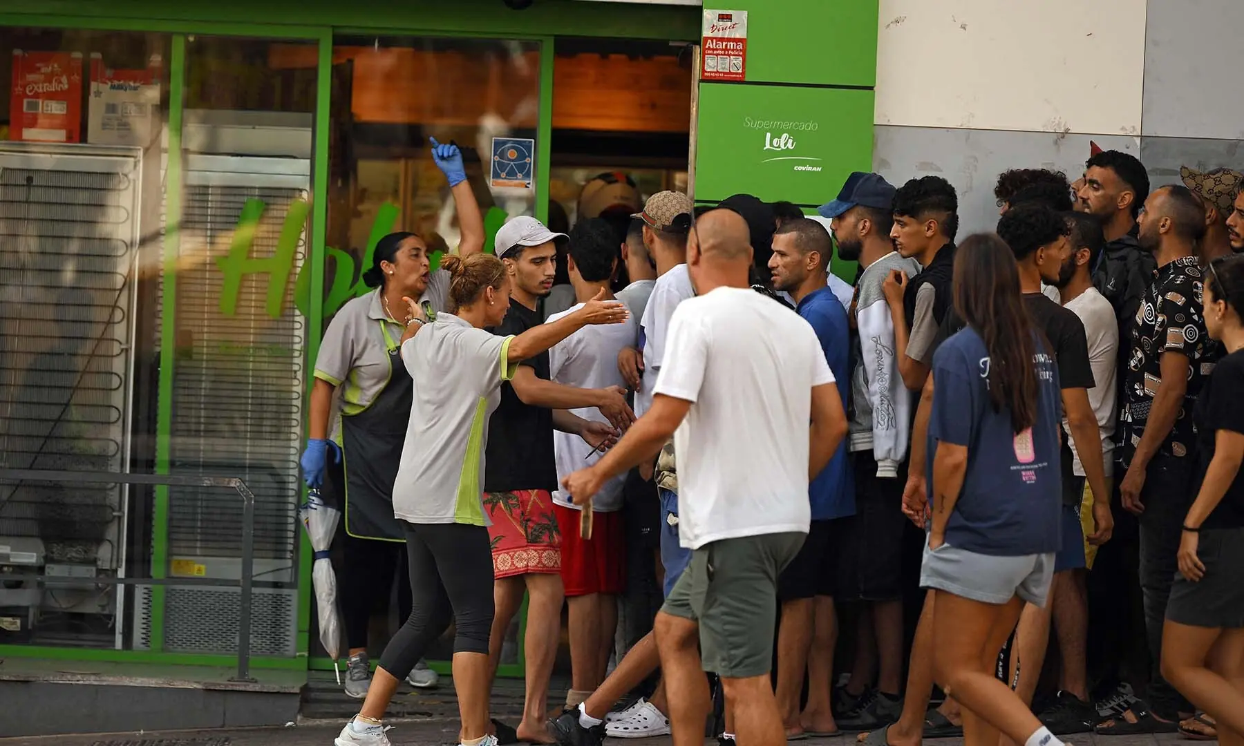 Supermarket employees (L) try to turn away a group of migrants attempting to enter the store in Spain’s north Africa’s Ceuta enclave on August 1, 2026. — AFP