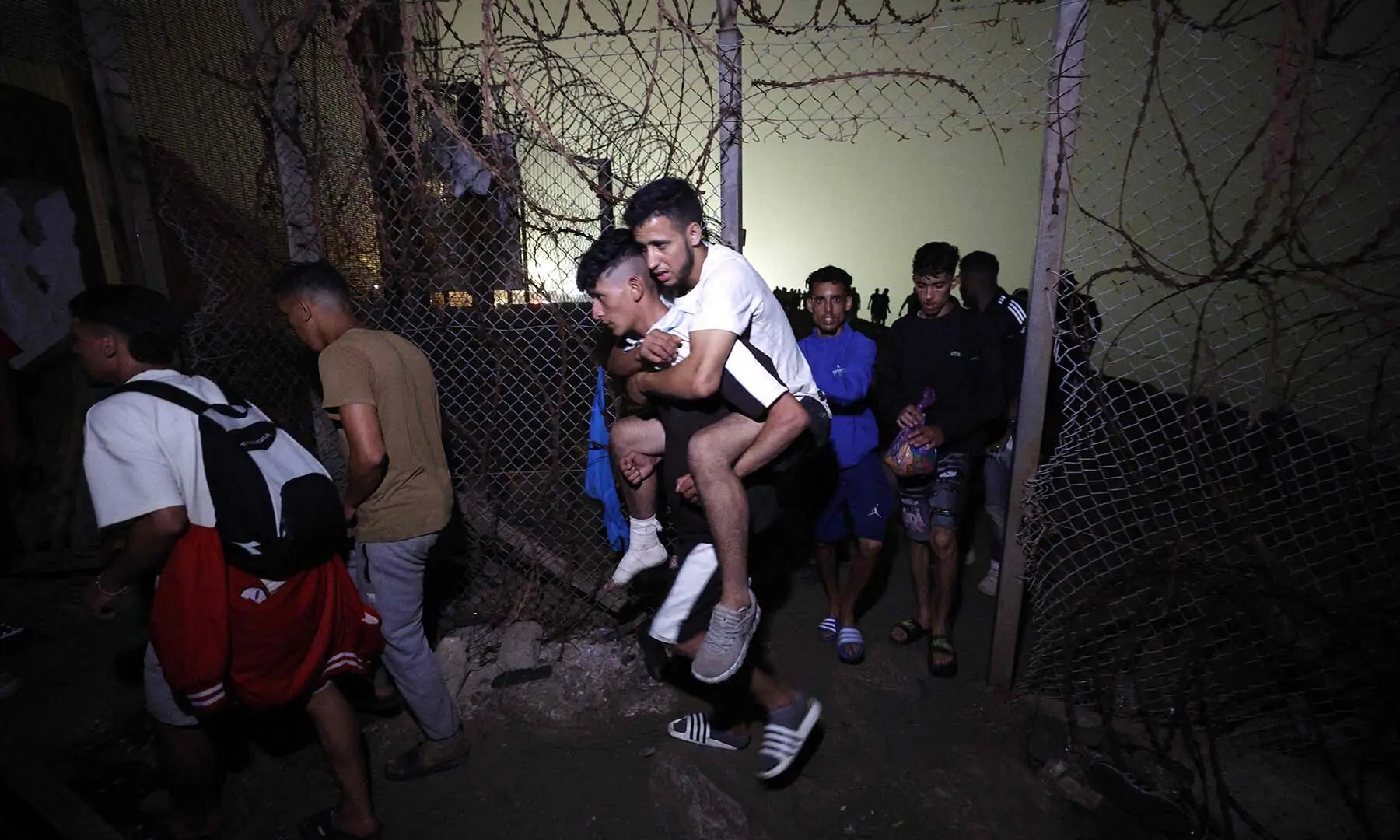 Migrants pass through a broken fence as they leave Spain's North African enclave of Ceuta towards the Moroccan town of Fnideq following an attempted crossing at the Bab Sebta border crossing, on August 1, 2026. — AFP Migrants pass through a broken fence as they leave Spain's North African enclave of Ceuta towards the Moroccan town of Fnideq following an attempted crossing at the Bab Sebta border crossing, on August 1, 2026. — AFP
