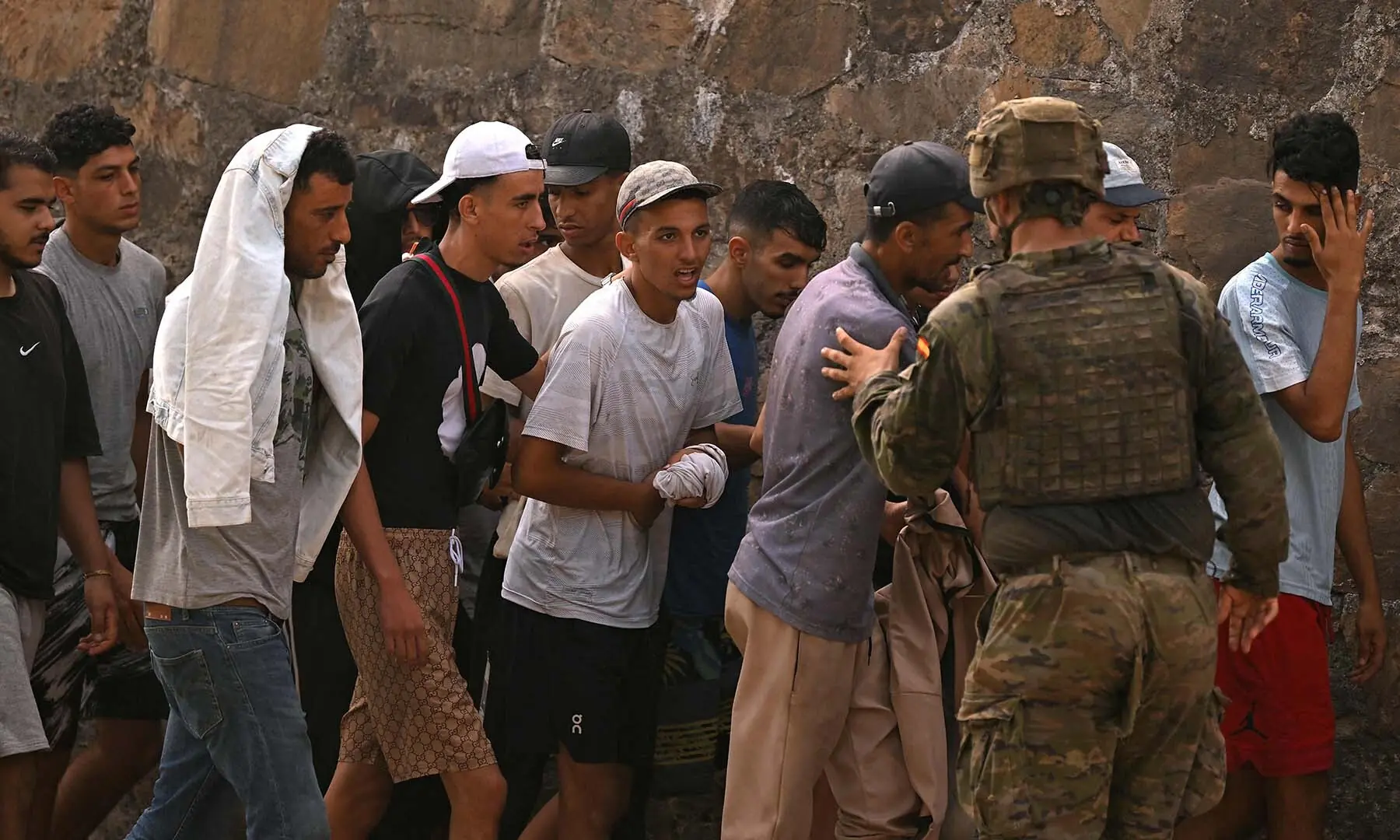 A Spanish soldier controls a group of migrants on their way back towards the Moroccan border, following their illegal crossing into the Spanish enclave of Ceuta, on August 1, 2026. — AFP