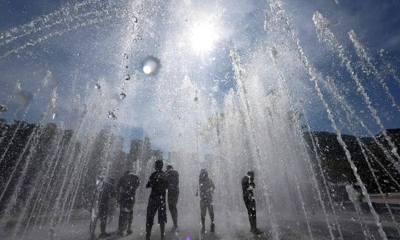 This picture taken on July 31, 2026 shows people playing in a fountain to cool off in Yangsan. &mdash; AFP