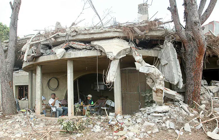 Residents sit at the entrance of their home destroyed by the Israeli military in the southern Lebanese village of Zawtar al-Gharbiyah.—AFP Residents sit at the entrance of their home destroyed by the Israeli military in the southern Lebanese village of Zawtar al-Gharbiyah.—AFP