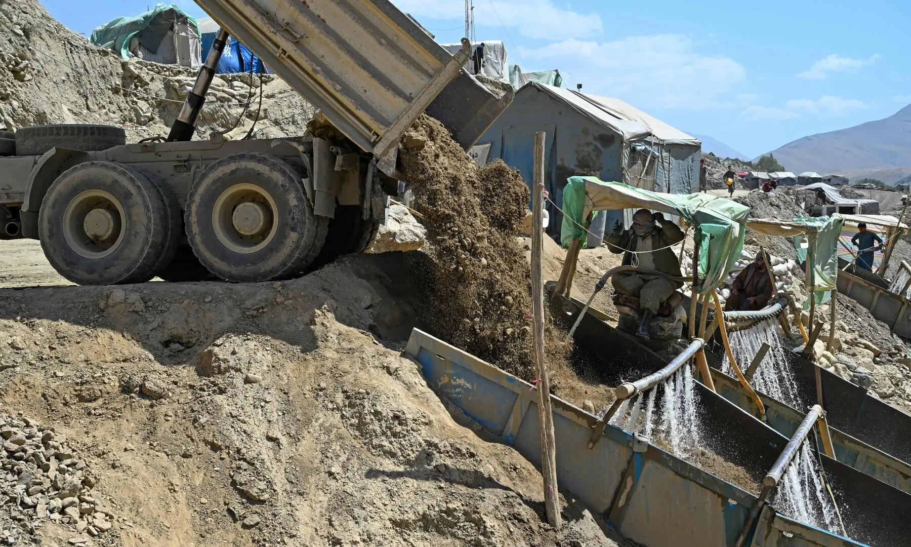 This photograph taken on July 28, 2026 shows Afghan miners pouring water over a sieve to separate dirt and stones from gold nuggets at Gulak-Dara valley in Shiwa area of Afghanistan&rsquo;s northeastern Badakhshan province. &mdash; AFP