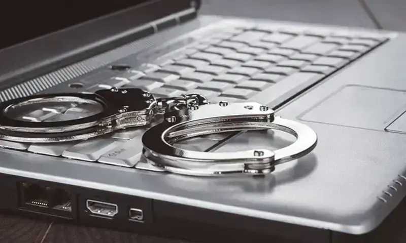 This file photo, used for representational purposes, shows handcuffs kept on top of a laptop. ─ AFP/File This file photo, used for representational purposes, shows handcuffs kept on top of a laptop. ─ AFP/File