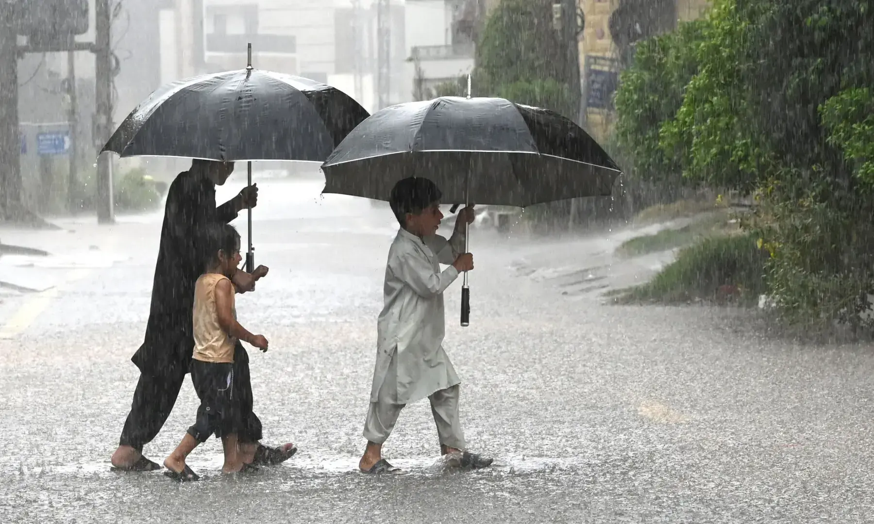 Children hold umbrellas whilst crossing a street as it rains in Peshawar on July 21, 2026. —AFP Children hold umbrellas whilst crossing a street as it rains in Peshawar on July 21, 2026. —AFP