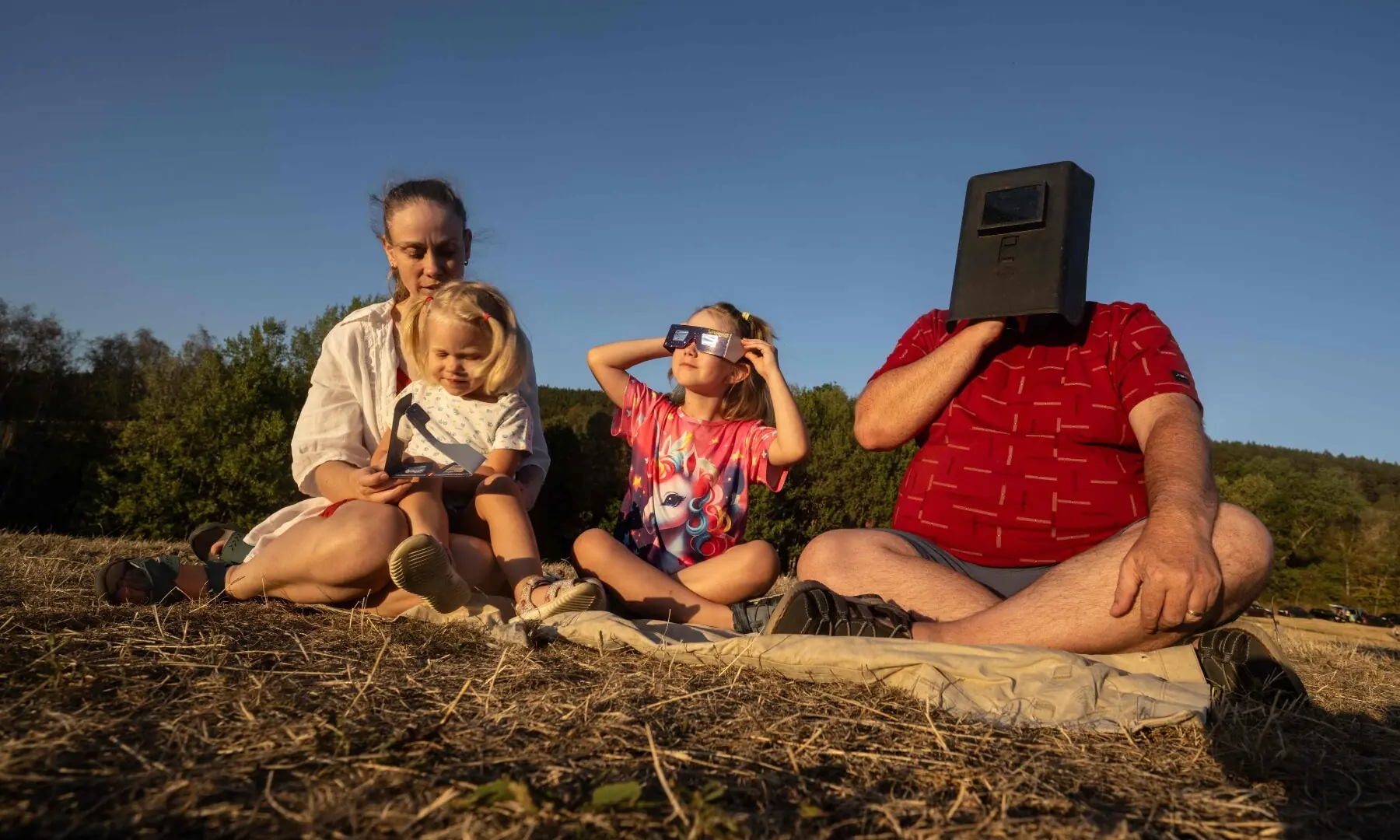  A family watches the partial solar eclipse through a mask and special glasses above Prachatice city, Czech Republic, on August 12, 2026. —AFP 