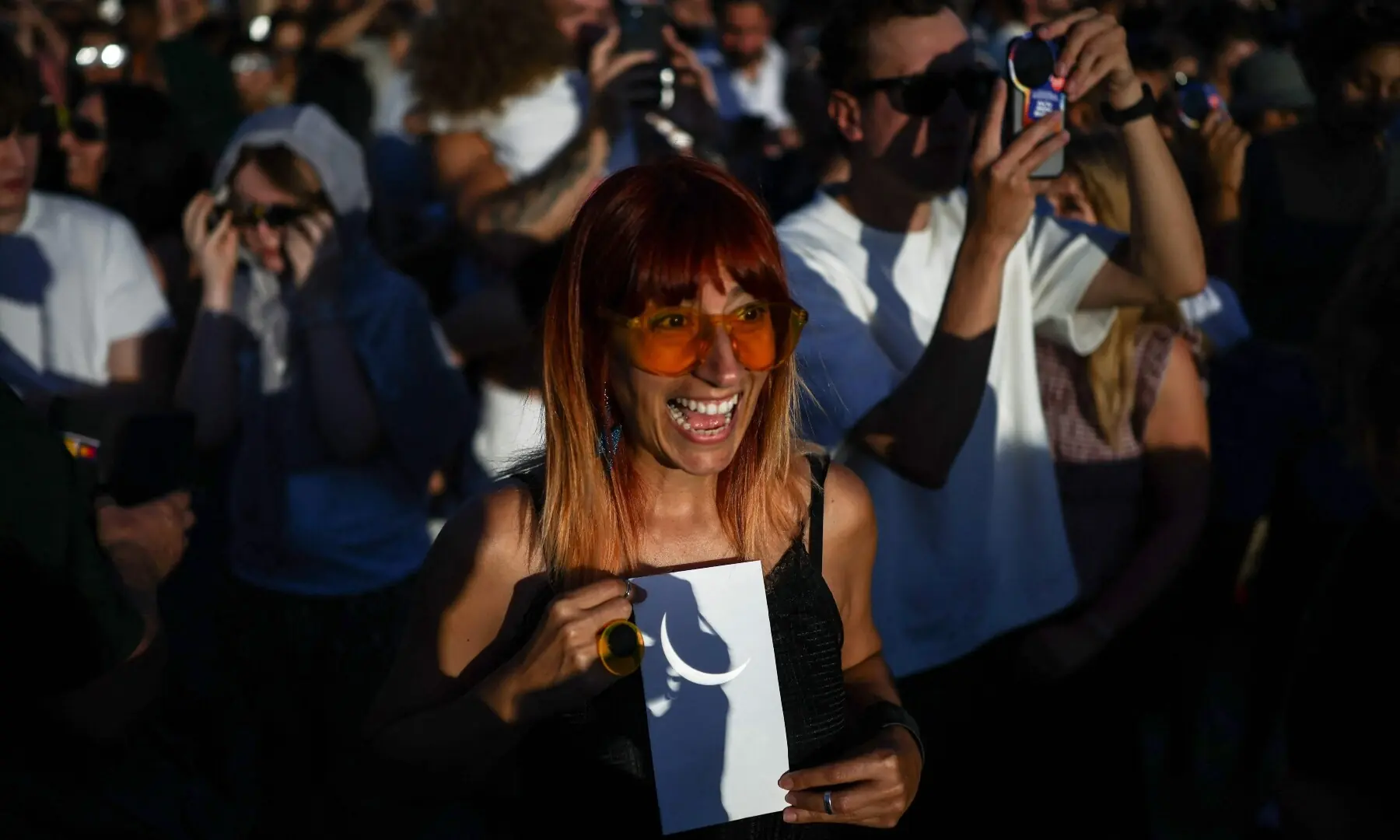  A woman (C) holds a piece of paper showing the eclipse refracted from binoculars, as people gather to watch a near total solar eclipse, with more than 90 percent of the Sun blocked by the Moon across Britain, from Primrose Hill in London on August 12, 2026. —AFP 