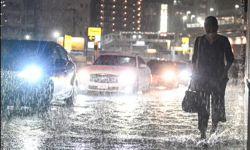 Cars pass a commuter on a flooded road near Chiba metro station in Chiba on August 13, 2026, as heavy rain swept through the area. — AFP Cars pass a commuter on a flooded road near Chiba metro station in Chiba on August 13, 2026, as heavy rain swept through the area. — AFP