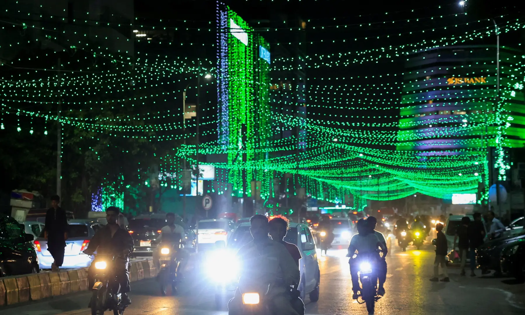 Commuters move along an illuminated road on the eve of Independence Day, in Karachi on August 13, 2026. — Reuters