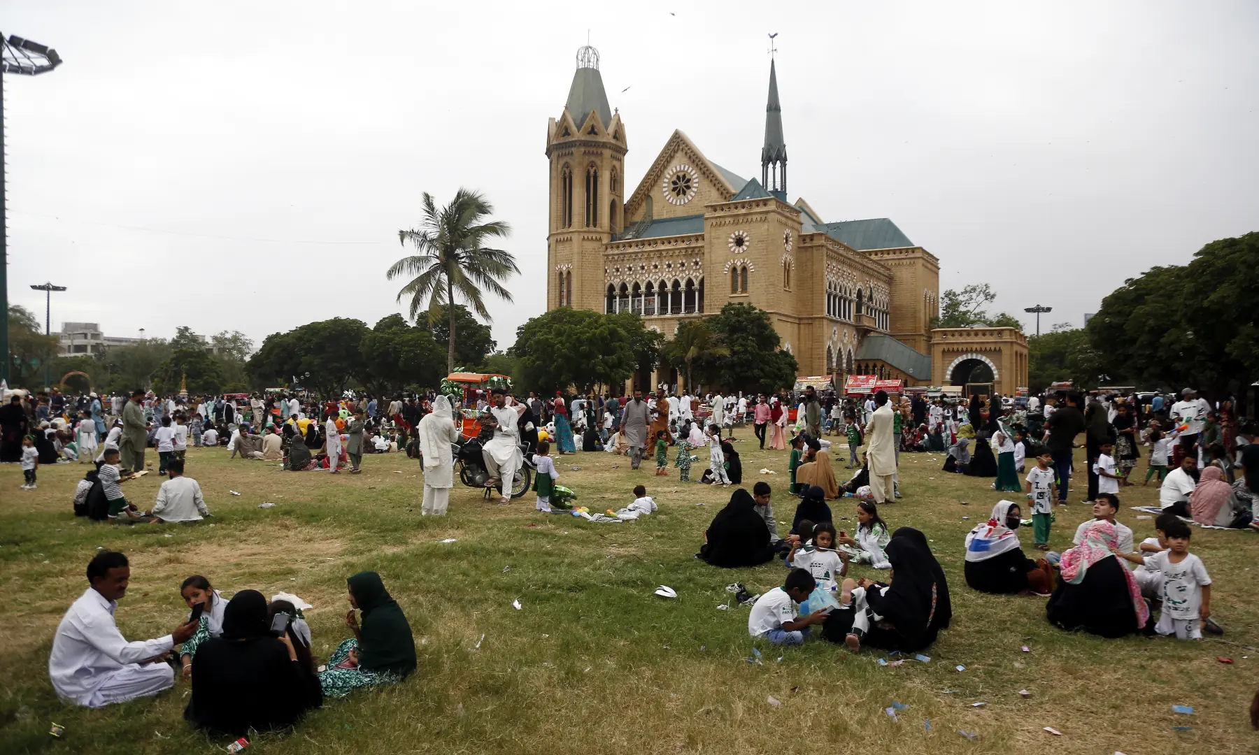 People sit in the grass during Independence Day celebrations at Frere Hall in Karachi on Aug 14, 2026. — White Star