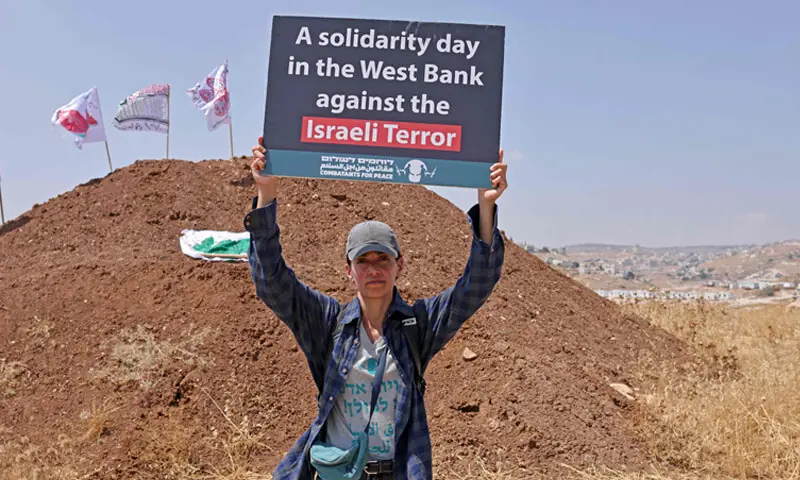 An activist holds a placard as she accompanies Palestinians to their property, which is at risk of being confiscated by Israeli settlers, in Beit Sahur, the occupied West Bank.—AFP An activist holds a placard as she accompanies Palestinians to their property, which is at risk of being confiscated by Israeli settlers, in Beit Sahur, the occupied West Bank.—AFP