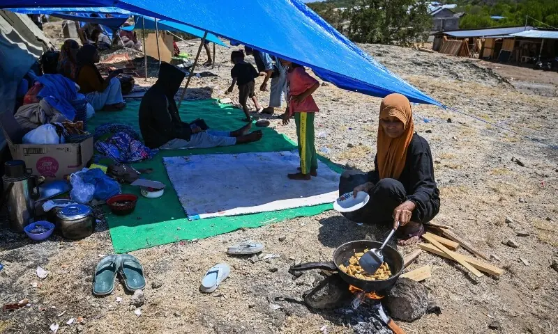 A vilager cooks next to a tent in an open field in Marapokot, Nagekeo, East Nusa Tenggara, on August 17, 2026, following a 7.7-magnitude earthquake. &mdash; AFP